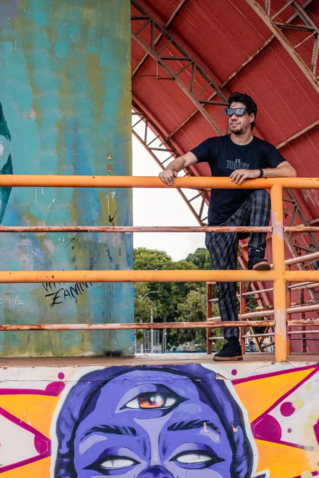 THUXX leaning on an orange railing under a steel arch